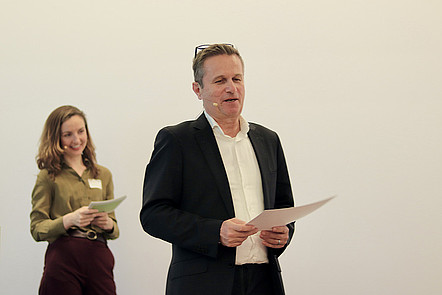 Dr. Rainer Müssner is in the center of the photo, greeting the winners. On the left, the moderator, Kristie Pladson is smiling.